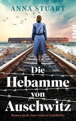 Das Buchcover zeigt eine Frau in einem blauen Mantel, die auf einem Bahngleis steht und zum Hintergrund blickt. Hinter ihr sind barrierefreie Zäune und verwitterte Gebäude zu erkennen, die eine bedrückende Atmosphäre erzeugen. Der Himmel ist von Wolken durchzogen und Vögel fliegen darüber. Der Titel „Die Hebamme von Auschwitz“ steht in großen, weißen Buchstaben, darunter der Zusatz „Roman nach einer wahren Geschichte“. Oben links ist der Name der Autorin „Anna Stuart“ in kleinerer Schrift zu sehen, das Verlagslogo ist rechts am Rand platziert.
