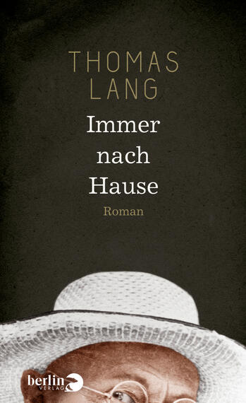 Das Buchcover zeigt einen dunklen Hintergrund, der eine melancholische Atmosphäre vermittelt. Im oberen Bereich steht der Name des Autors „THOMAS LANG“ in goldener Schrift. Darunter befindet sich der Titel „Immer nach Hause“ in weißer, klarer Typografie. Unter dem Titel ist das Wort „Roman“ in kleinerer Schriftgröße zu lesen. Die untere Hälfte des Covers zeigt den Rand eines breiten, weißen Huts, der das Bild abrundet und auf den Hauptcharakter hindeutet.