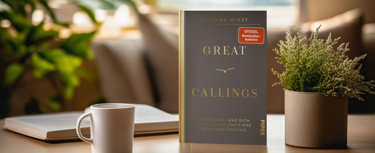 „Great Callings“ steht auf einem Tisch. Daneben eine Tasse, ein Buch und eine Pflanze.