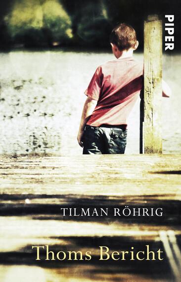 Das Buchcover zeigt einen Jungen in einem roten T-Shirt, der auf einem Holzsteg steht und in die Ferne blickt. Der Steg verläuft über eine spiegelnde Wasserfläche, die die natürliche Umgebung leicht reflektiert. Der Hintergrund ist unscharf und vermittelt eine melancholische Stimmung. Oben rechts ist in weißer Schrift der Verlagsname „PIPER“ zu sehen, während der Titel „Thoms Bericht“ und der Autor „Tilman Röhrig“ in eleganter, serifenloser Schrift angebracht sind.