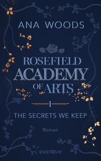 Das Buchcover zeigt einen dunkelblauen Hintergrund, der mit goldenen und weißen floralen Elementen verziert ist. In der Mitte steht der Titel „ROSEFIELD ACADEMY OF ARTS“ in großen, eleganten Buchstaben, darunter befindet sich die Unterzeile „1 – THE SECRETS WE KEEP“ in kleineren Schriftgrößen. Der Name der Autorin, „ANA WOODS“, ist oben platziert. Die gesamte Gestaltung vermittelt eine geheimnisvolle und künstlerische Atmosphäre.