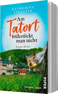Das Buchcover zeigt eine idyllische Landschaft mit einem historischen Fachwerkhaus im Vordergrund. Ein Eichhörnchen hält eine Nuss und blickt neugierig aus dem Bild. Der Hintergrund ist in sanften Grüntönen gehalten, während der Himmel in einem strahlenden Blau erscheint. Der Titel „Am Tatort frühstückt man nicht“ ist in lebhaftem Orange und klarer Schrift gesetzt, unterhalb befindet sich der Schriftzug „Taunus-Krimi“ in schwarzer Schrift. Oben auf dem Cover steht der Name der Autorin, „Katharina Spengler“, in blauer Schrift.