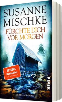 Das Buchcover zeigt ein mysteriöses, einsames Holzhaus, das von düsterem Nebel umgeben ist. Im Vordergrund sind verstreute Steine und eine unheimliche Atmosphäre sichtbar. Der Titel „Fürchte dich vor Morgen“ steht in großen, orangefarbenen Buchstaben, während der Autor „Susanne Mischke“ darüber in schlichter, weißer Schrift platziert ist. In der oberen linken Ecke befindet sich ein rotes Etikett mit der Aufschrift „SPIEGEL Bestseller“ in weißer Schrift sowie der Hinweis „Jetzt als Taschenbuch“. Das Cover vermittelt ein Gefühl von Spannung und Ungewissheit.