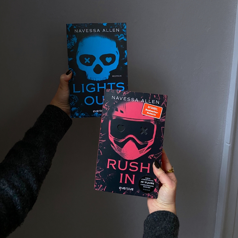 „Rush In“ und „Lights Out“ werden vor eine grauen Wand gehalten