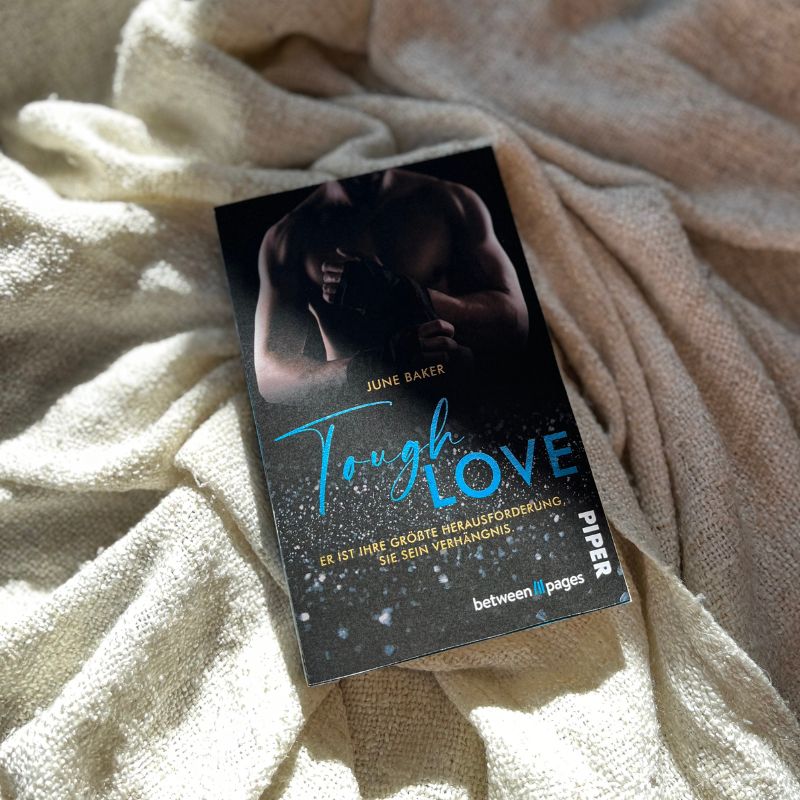 "Tough Love" von June Baker liegt auf einer Decke im Sonnenlicht.