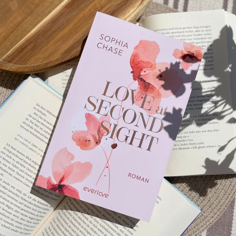 „Love at Second Sight“ von Sophia Chase liegt auf aufgeschlagenen Büchern