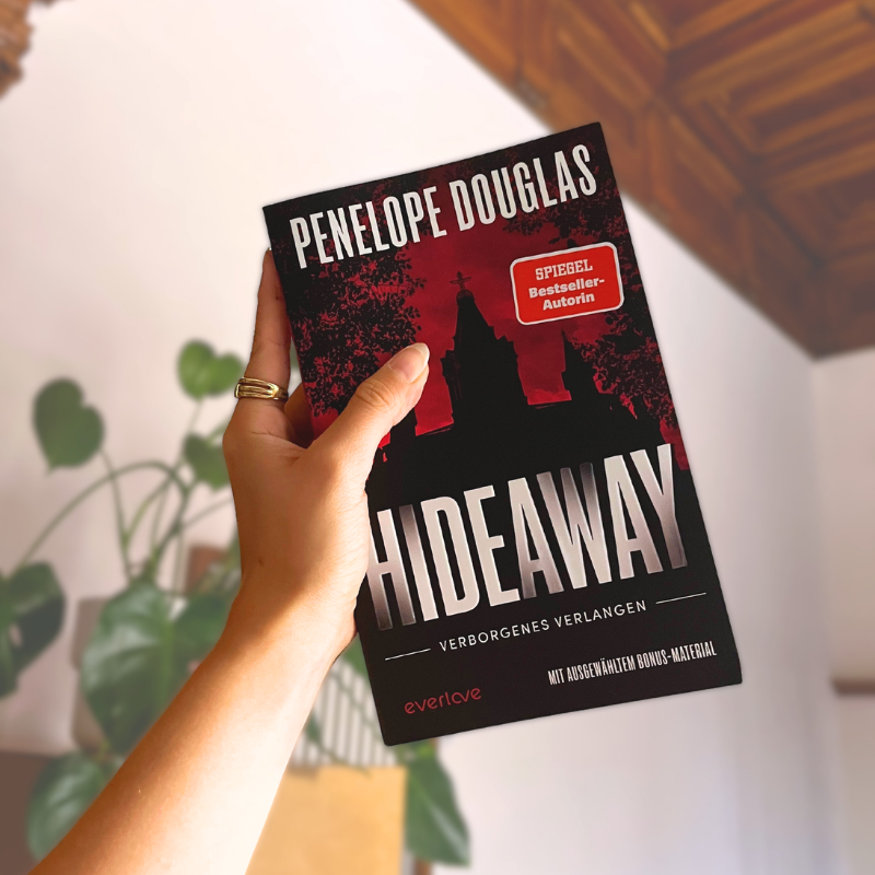 „Hideaway“ von Penelope Douglas wird in einer Hand vor Pflanzen gehalten