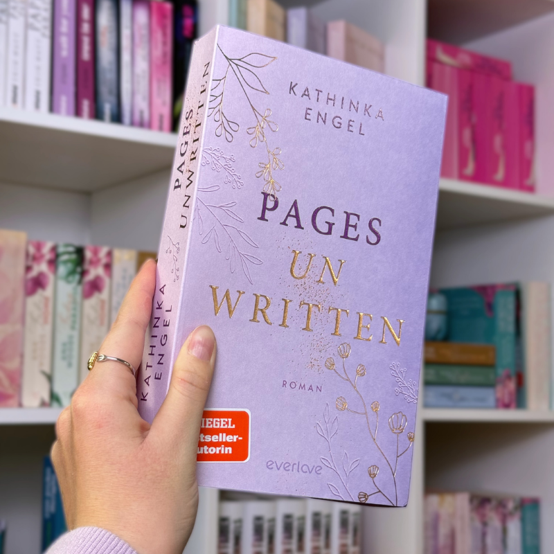 „Pages Unwritten“ von Kathinka Engel wird vor einem Bücherregal gehalten.