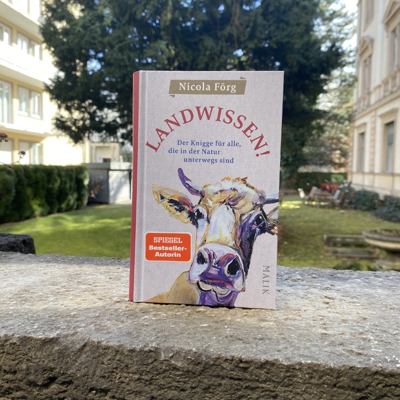 "Landwissen" steht auf einer Mauer. Im Hintergrund ist ein Garten zu sehen.
