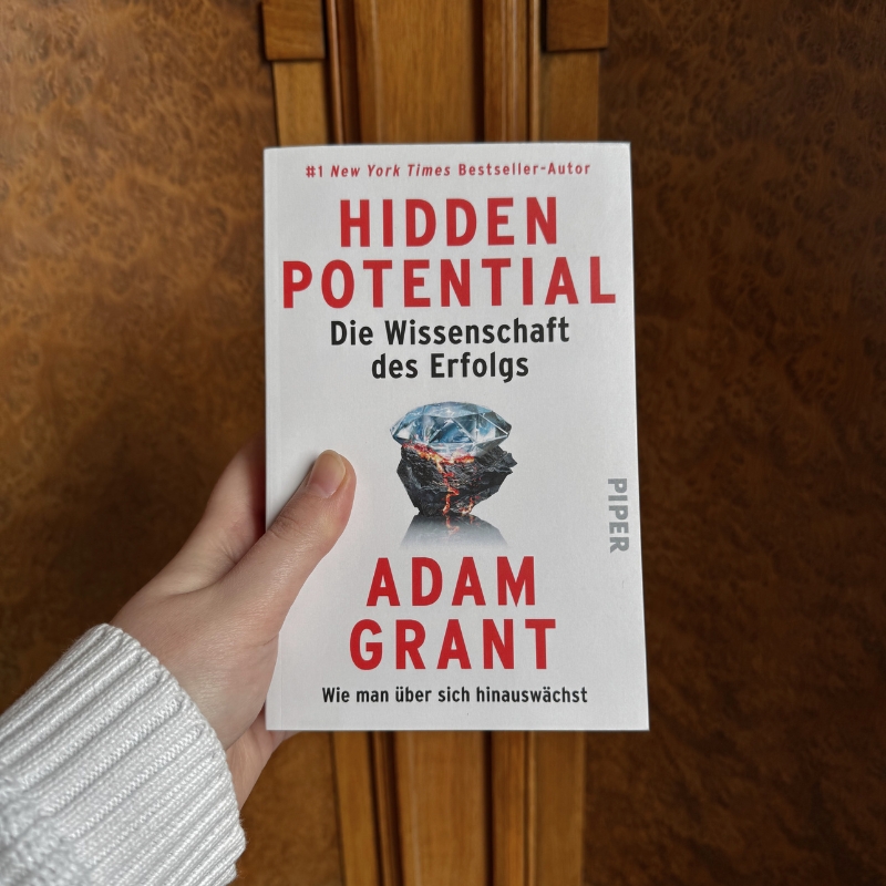 „Hidden Potential“ wird von einer Hand vor Holz gehalten