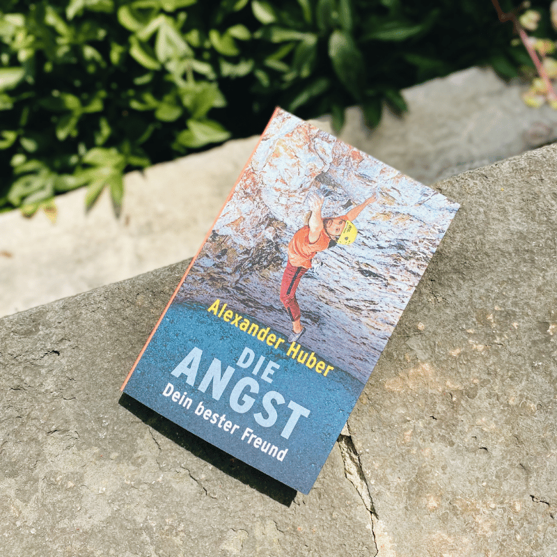 „Die Angst – Dein bester Freund“ von Alexander Huber liegt auf einem Stein