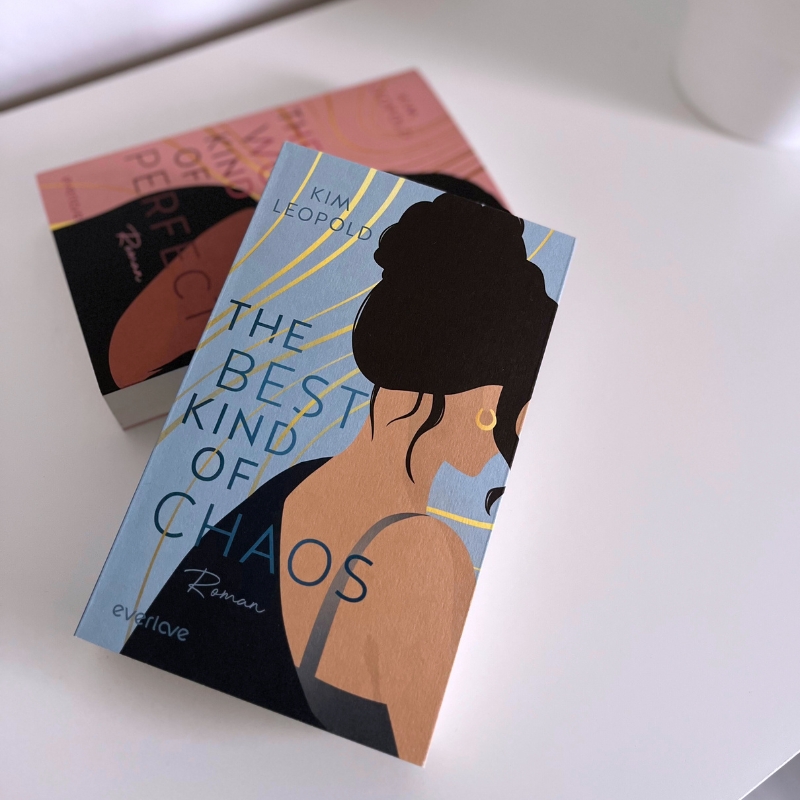 „The Best Kind of Chaos“ liegt schräg über „The Worst Kind of Perfect“ auf einem weißen Tisch