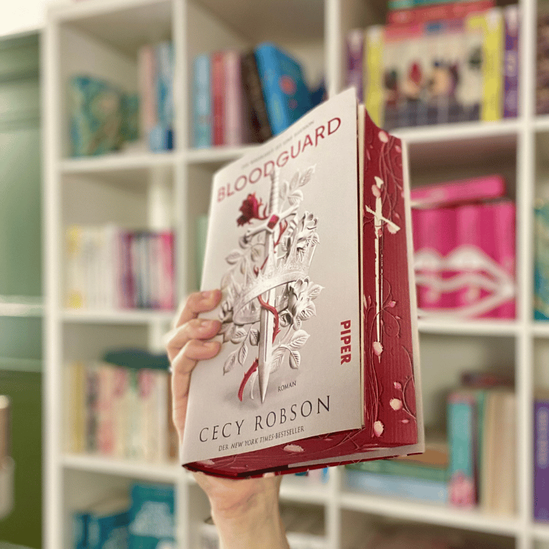 „Bloodguard“ von Cecy Robson wird vor einem Bücherregal gehalten