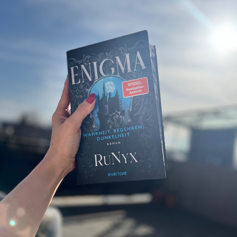 "Enigma" wird von einer Hand gen Himmel gehalten.