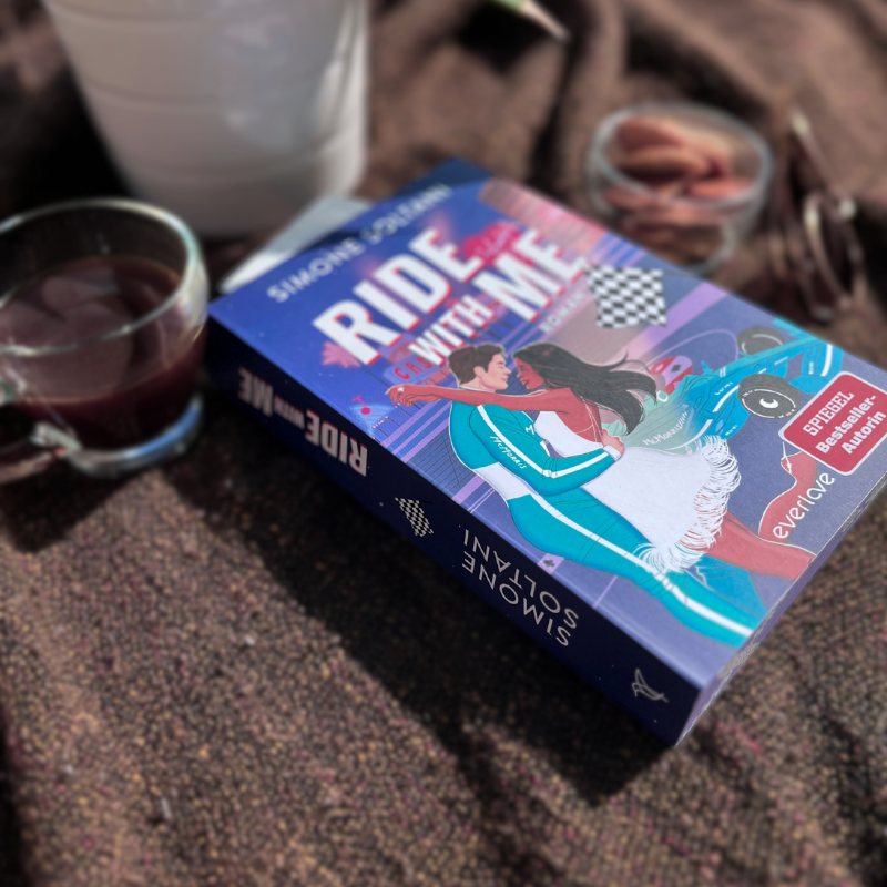 „Ride with me“ von Simone Soltani liegt auf einer Decke neben Tee und Mandeln.